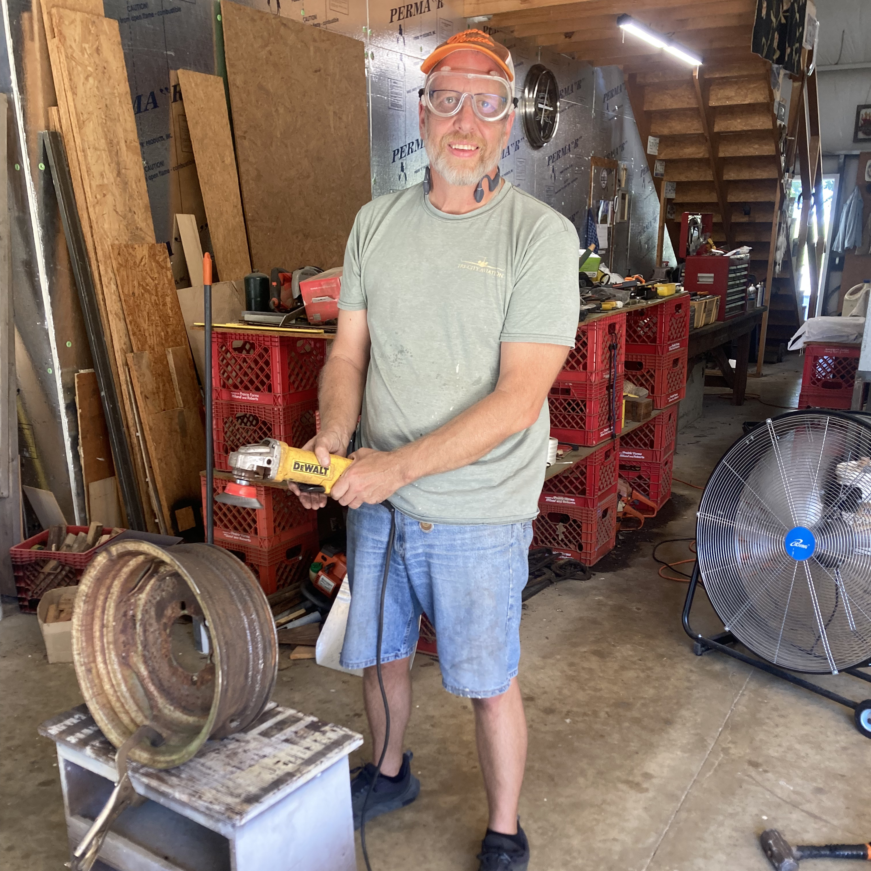 Man in a shop wearing goggles and holding an angle grinder