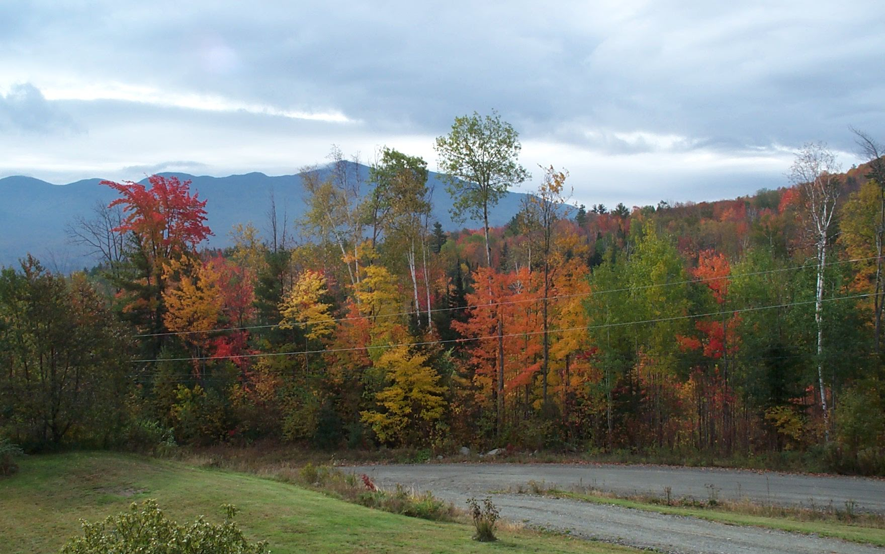 A New England landscape in fall with colorful trees in front of a mountain