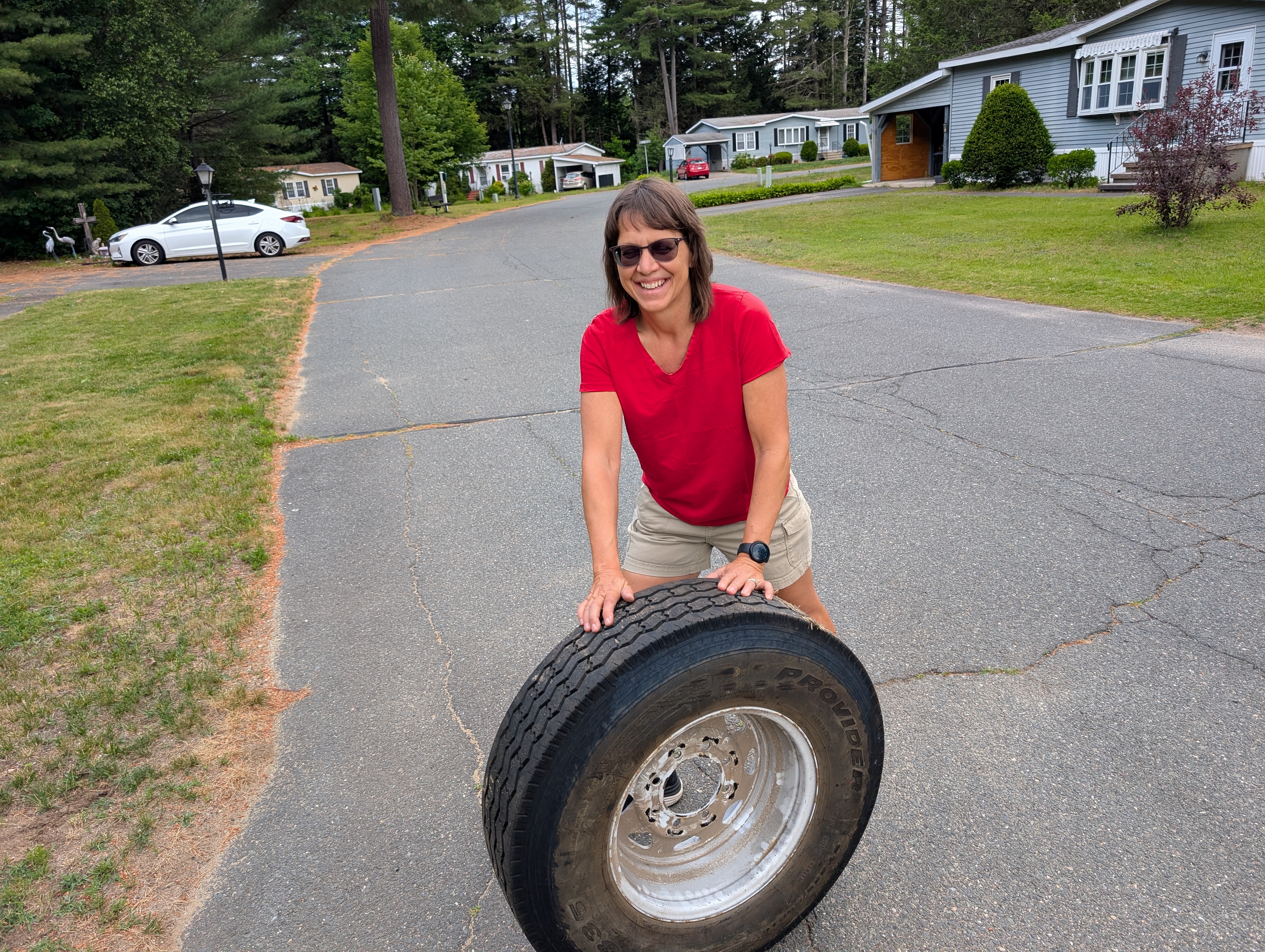 Woman rolling a tire across a road