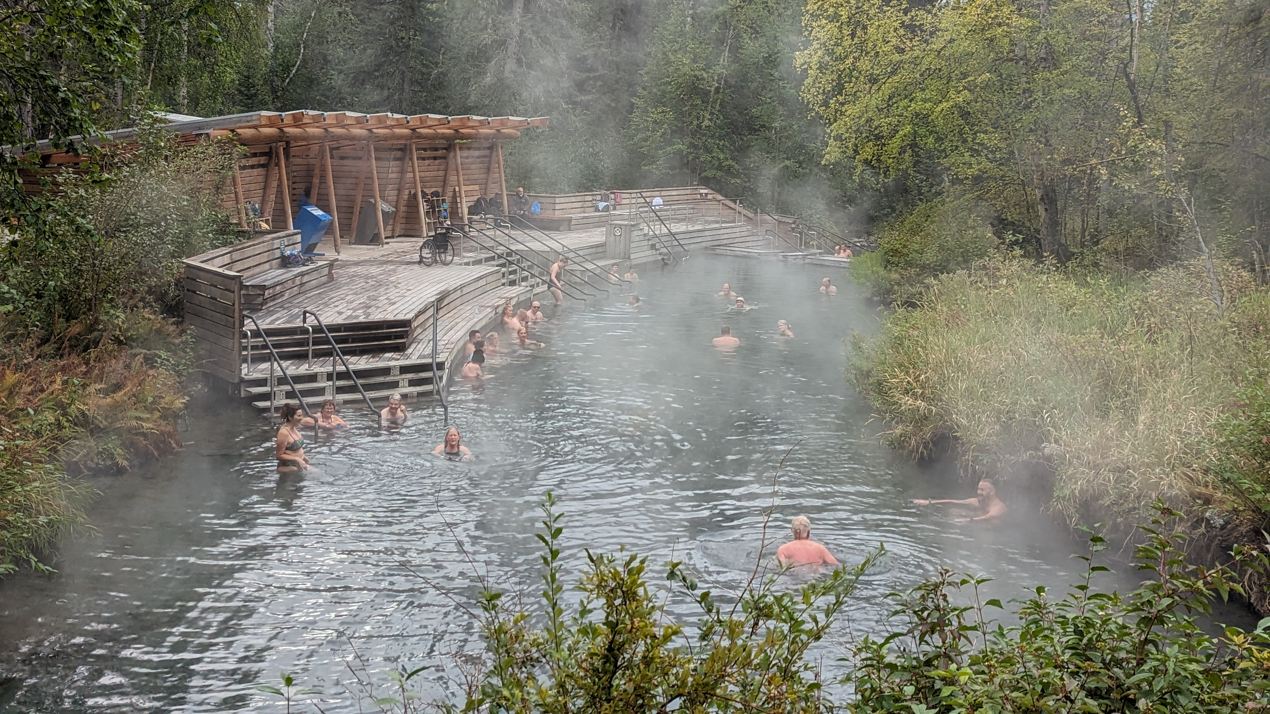 People in a hot springs pool with steam rising
