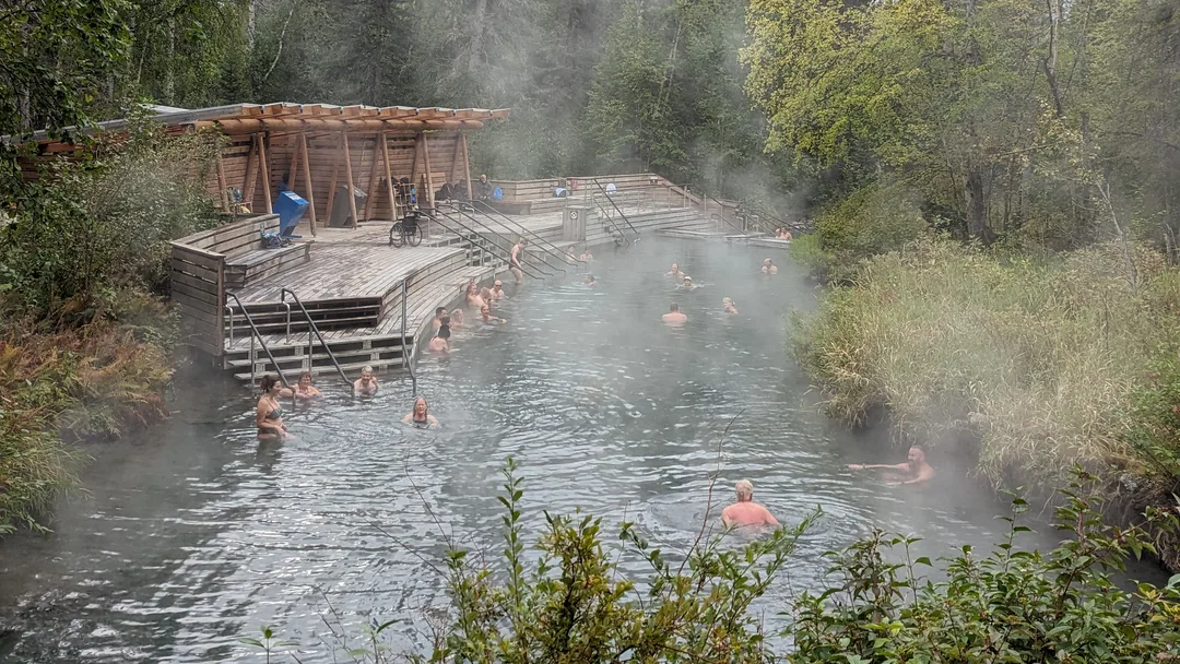 People in a hot springs pool with steam rising