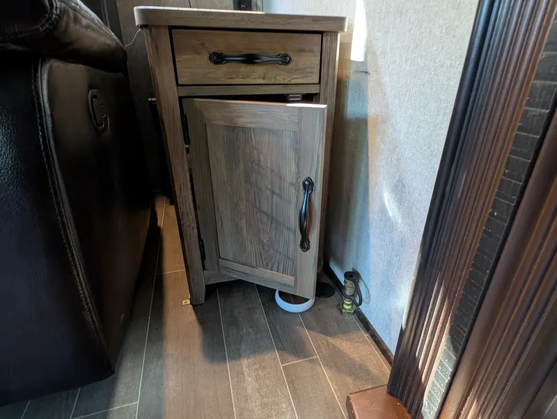 An open door on an  end table with pieces from inside it on the floor