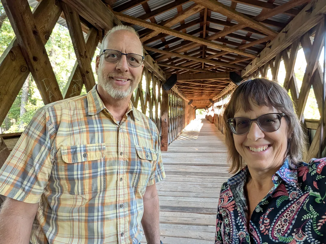 Bob and Lana Gates standing at the entrance to the Clarkson-Legg Covered Bridge in Alabama