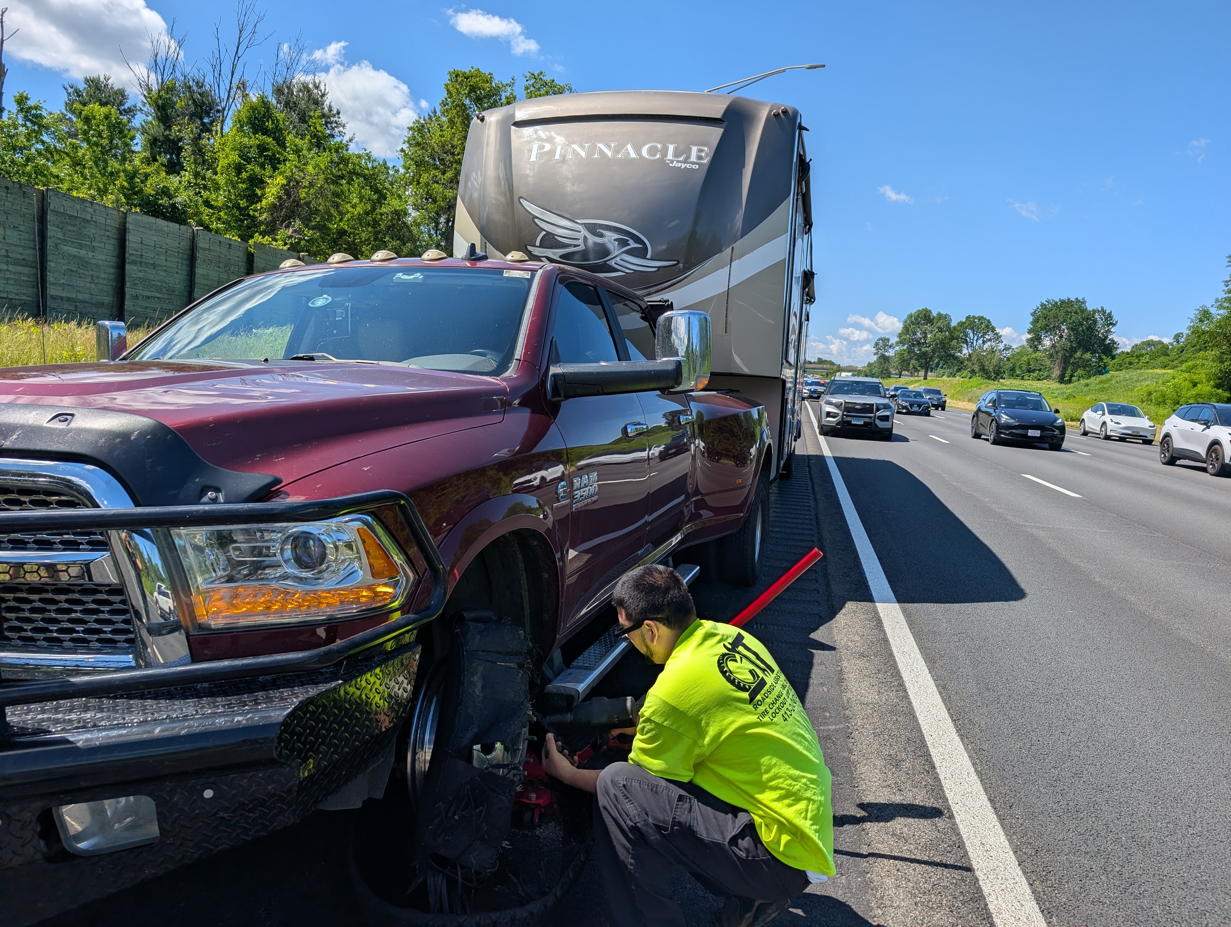 Service tech working on a truck tire on the side of a freeway