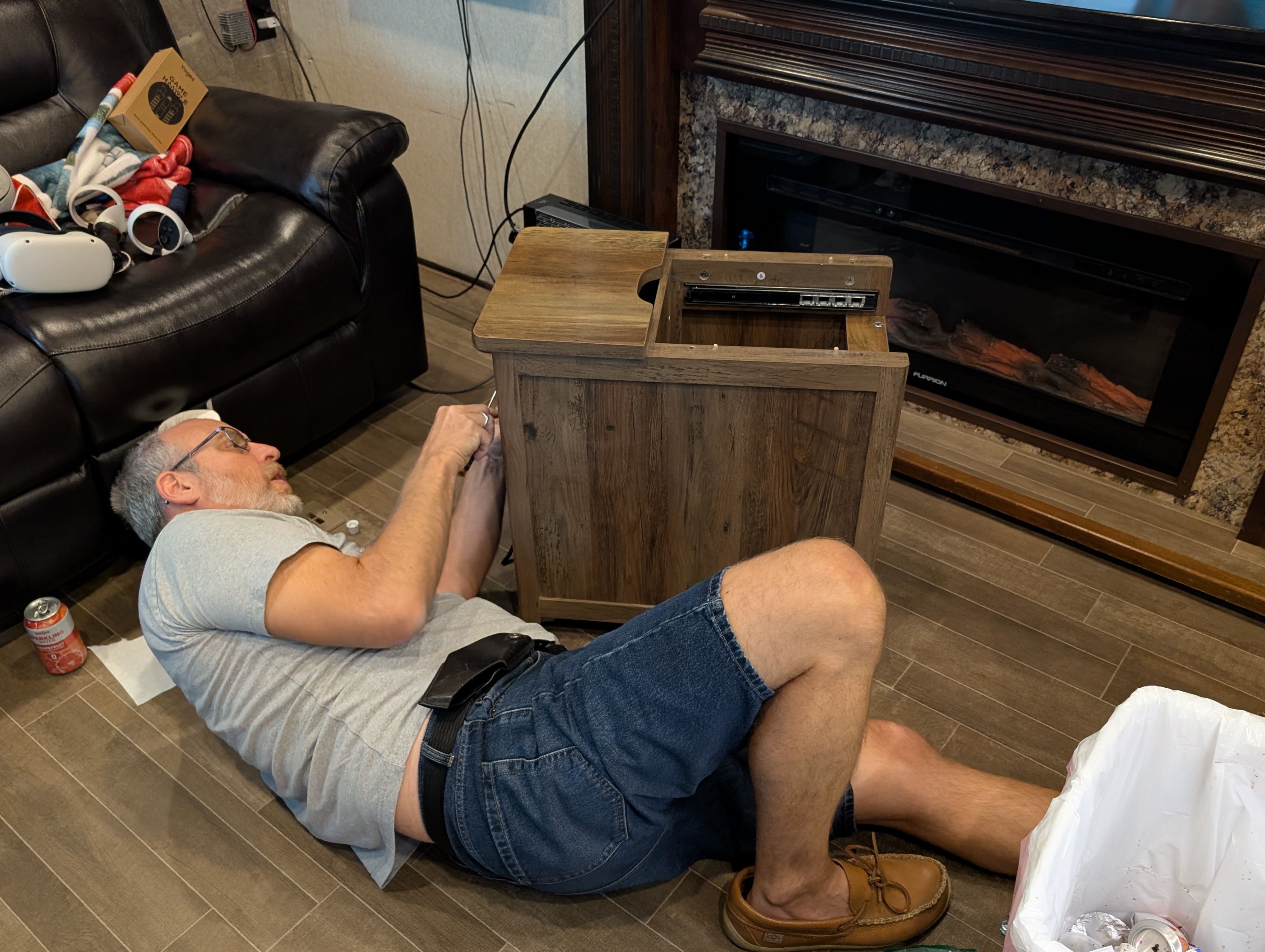 A man on his back on an RV floor repairing a table
