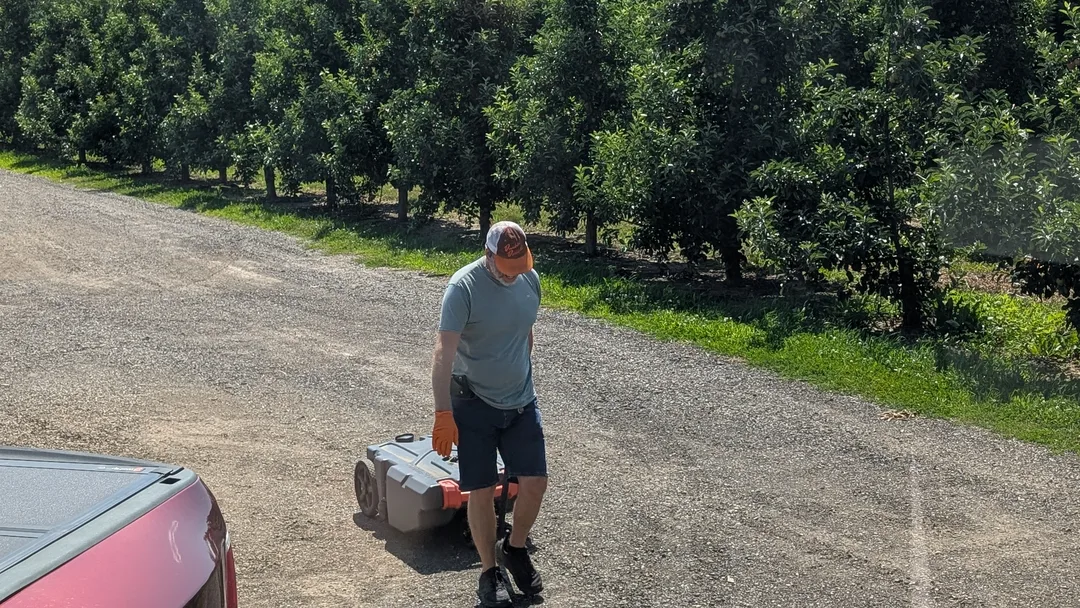 Man hauling a waste tank tote in front of trees