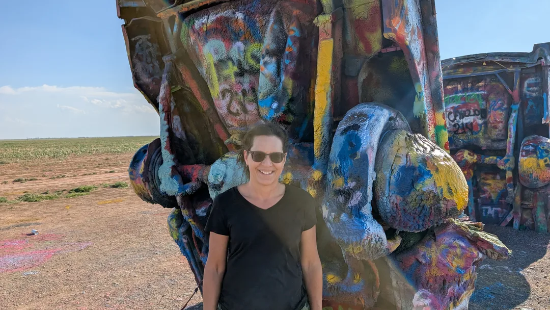 Lana Gates in front of a paint-caked vehicle at Cadillac Ranch
