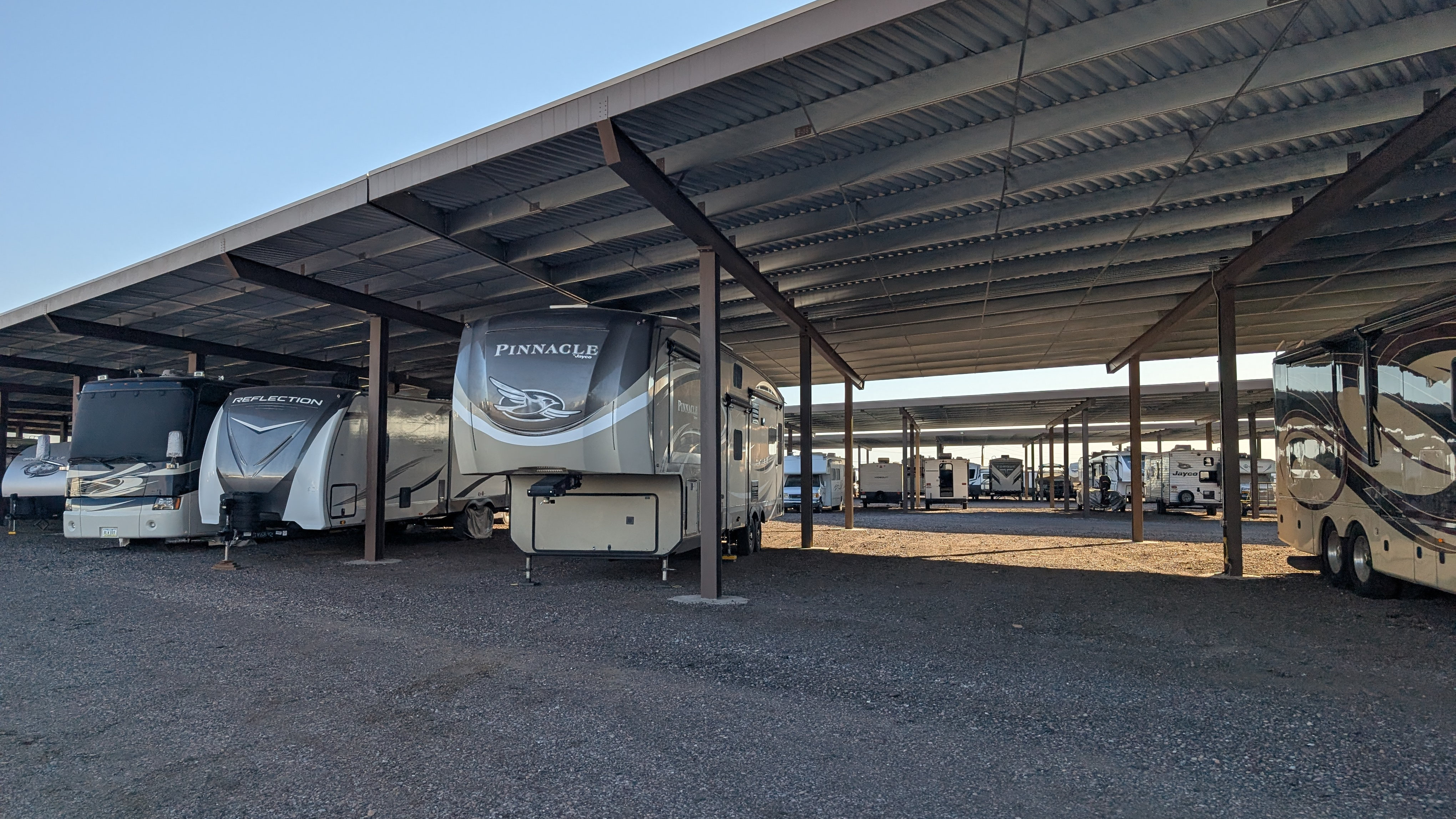 A fifth wheel under an awning at a storage lot