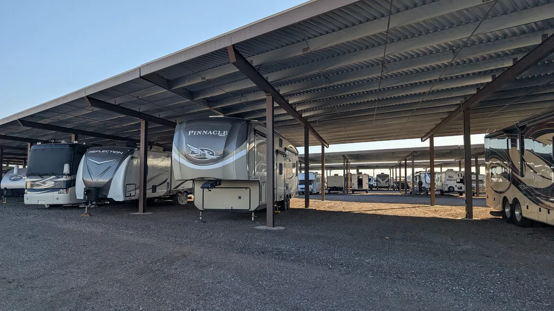 A fifth wheel under an awning at a storage lot