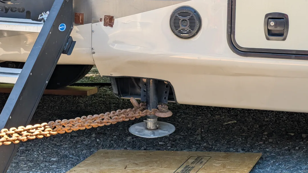 A taut chain wrapped around a stabilizer under an RV