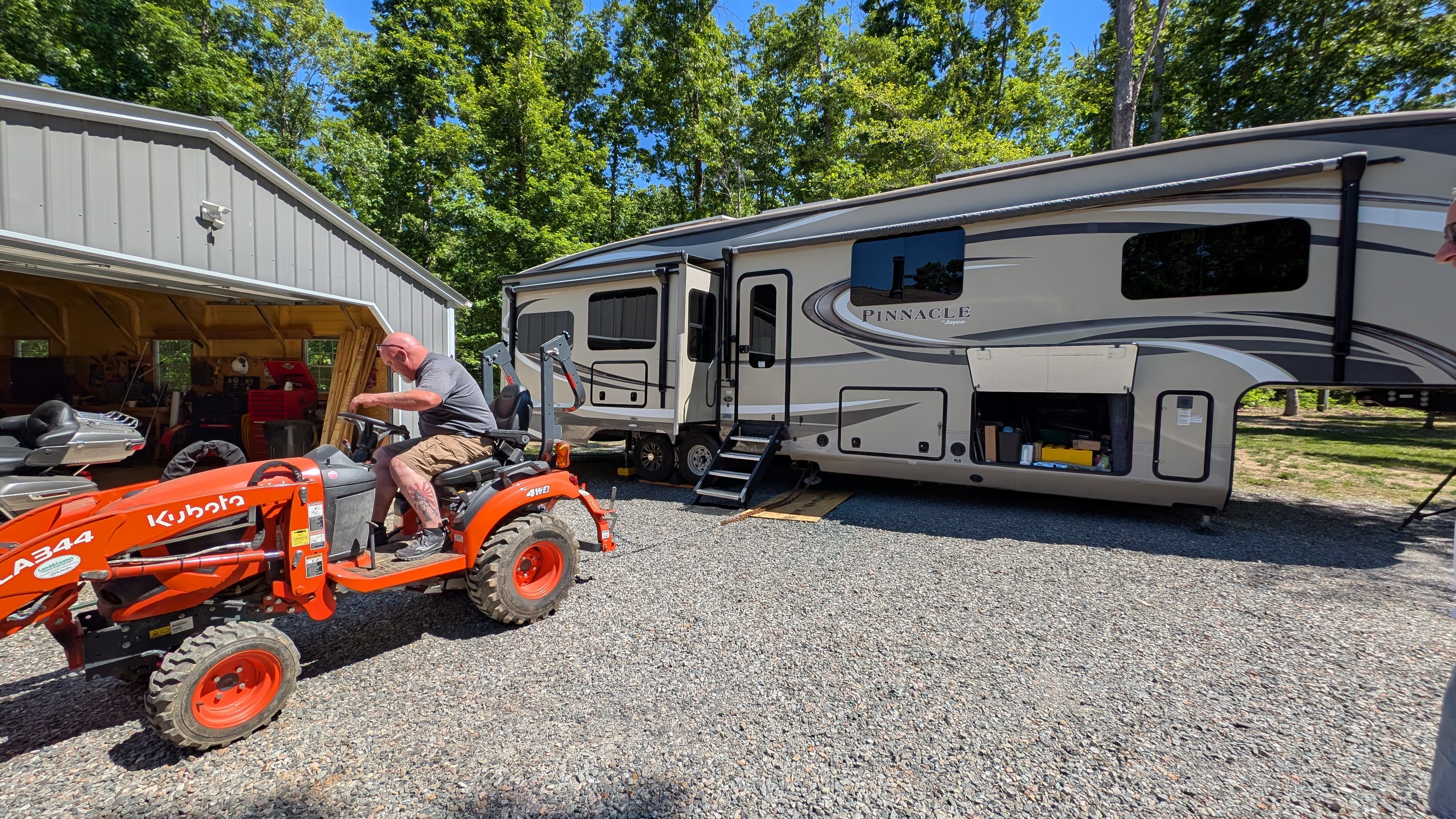 Man on an orange tractor on the side of a fifth wheel RV